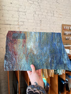 Hand holding a textured glass sheet against a brick wall.