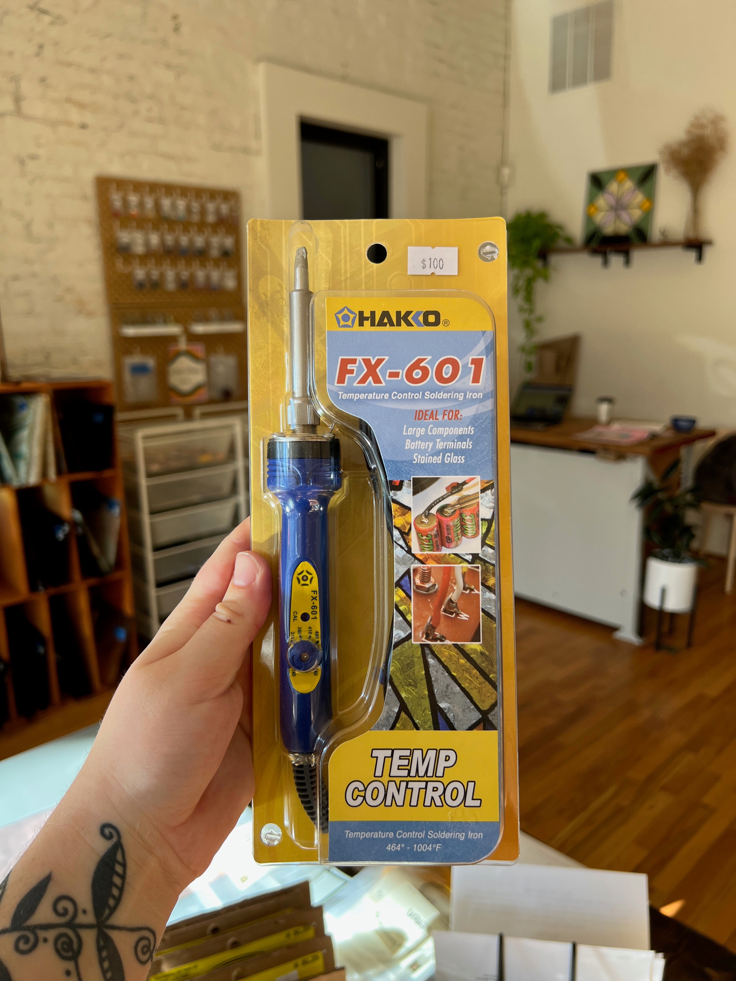 HAKKO FX-601 soldering iron in packaging held by a person with tattoos.