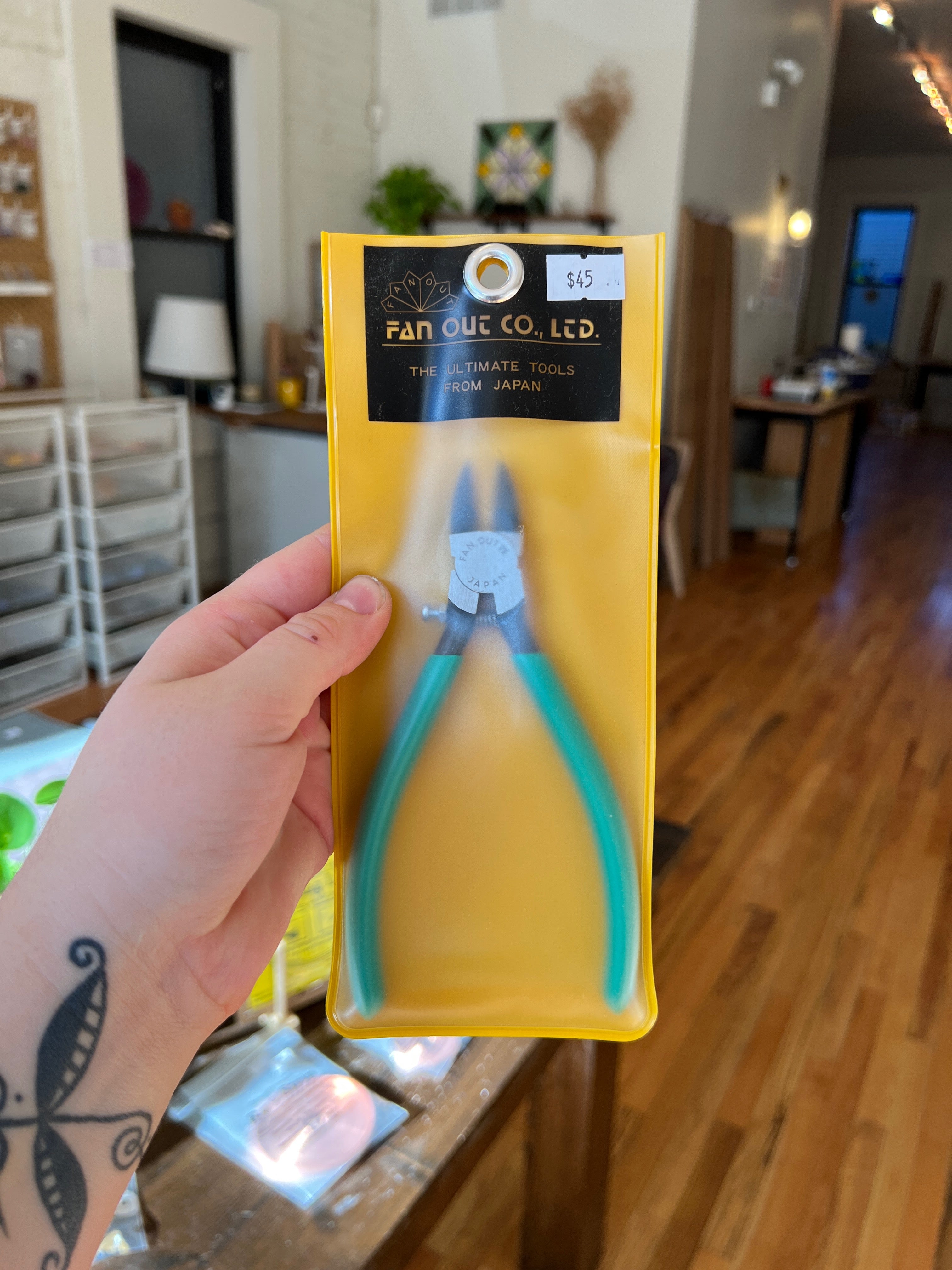 Hand holding a pair of pliers in yellow packaging with 'Fan Out Co. Ltd.' branding.