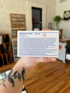 Hand holding a warning label for ammonium chloride in an indoor setting.