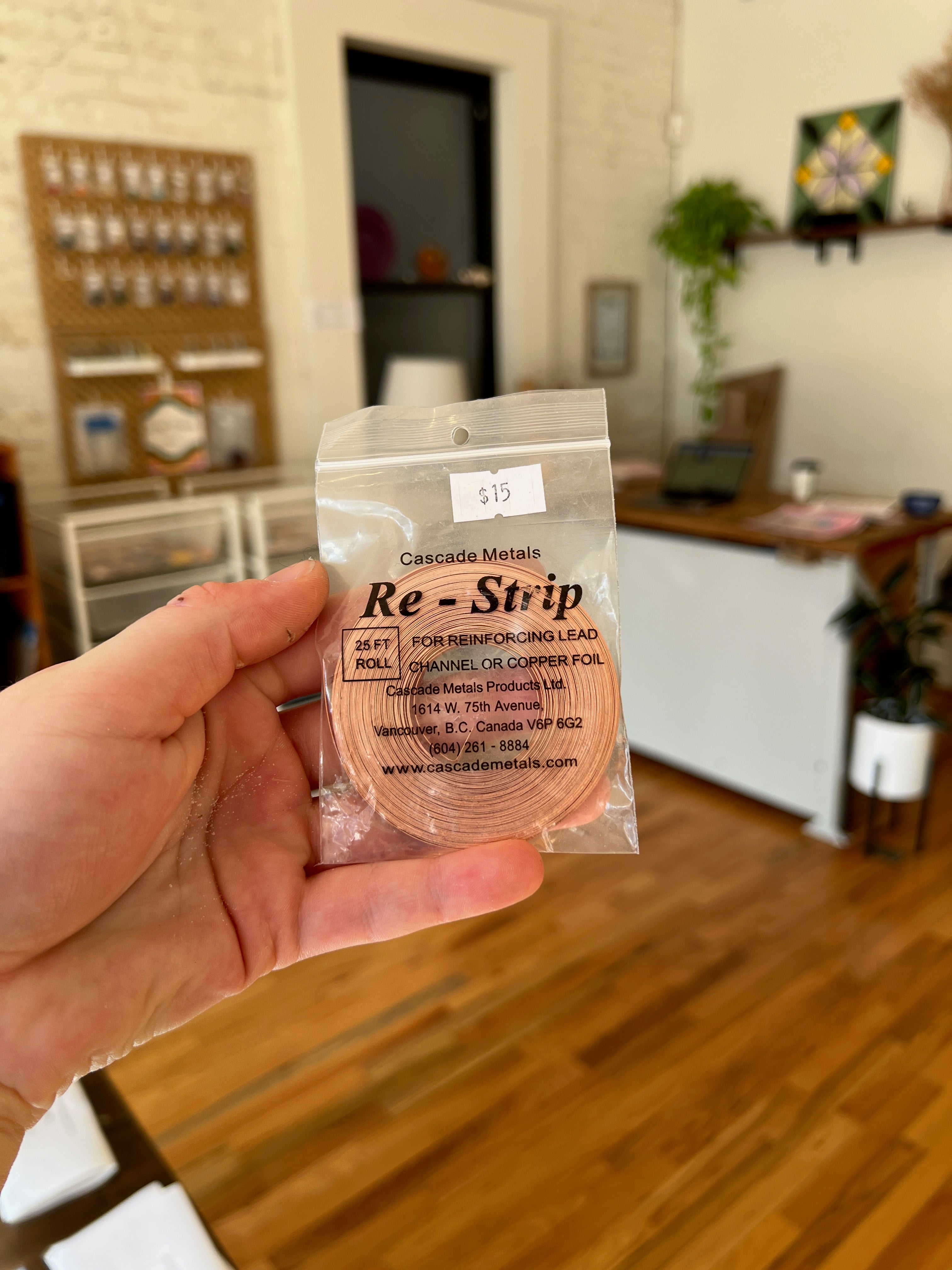 Hand holding a package labeled 'Re-Strip' in a home setting