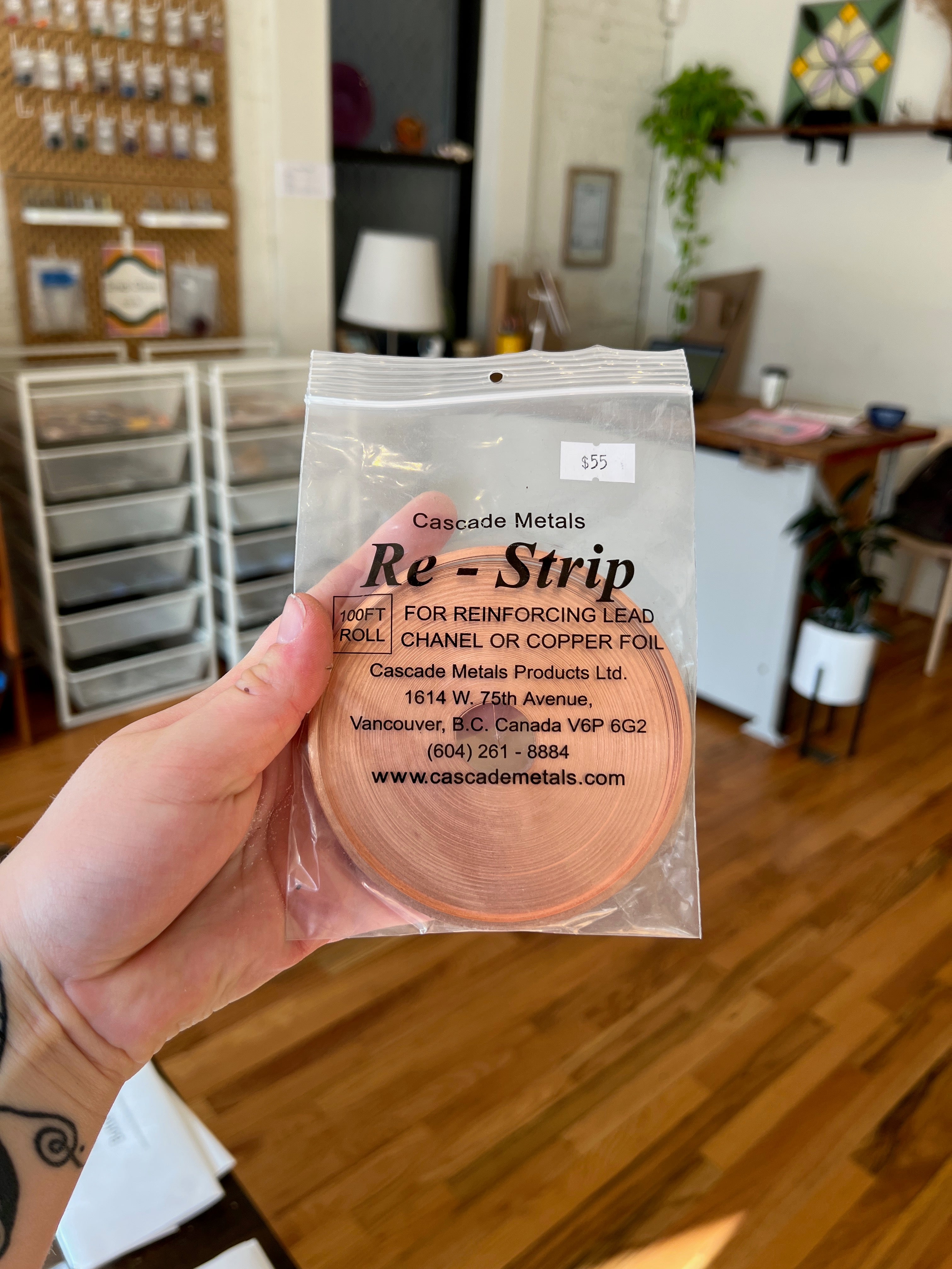 Hand holding a package of Cascade Metals Re-Strip in a home setting