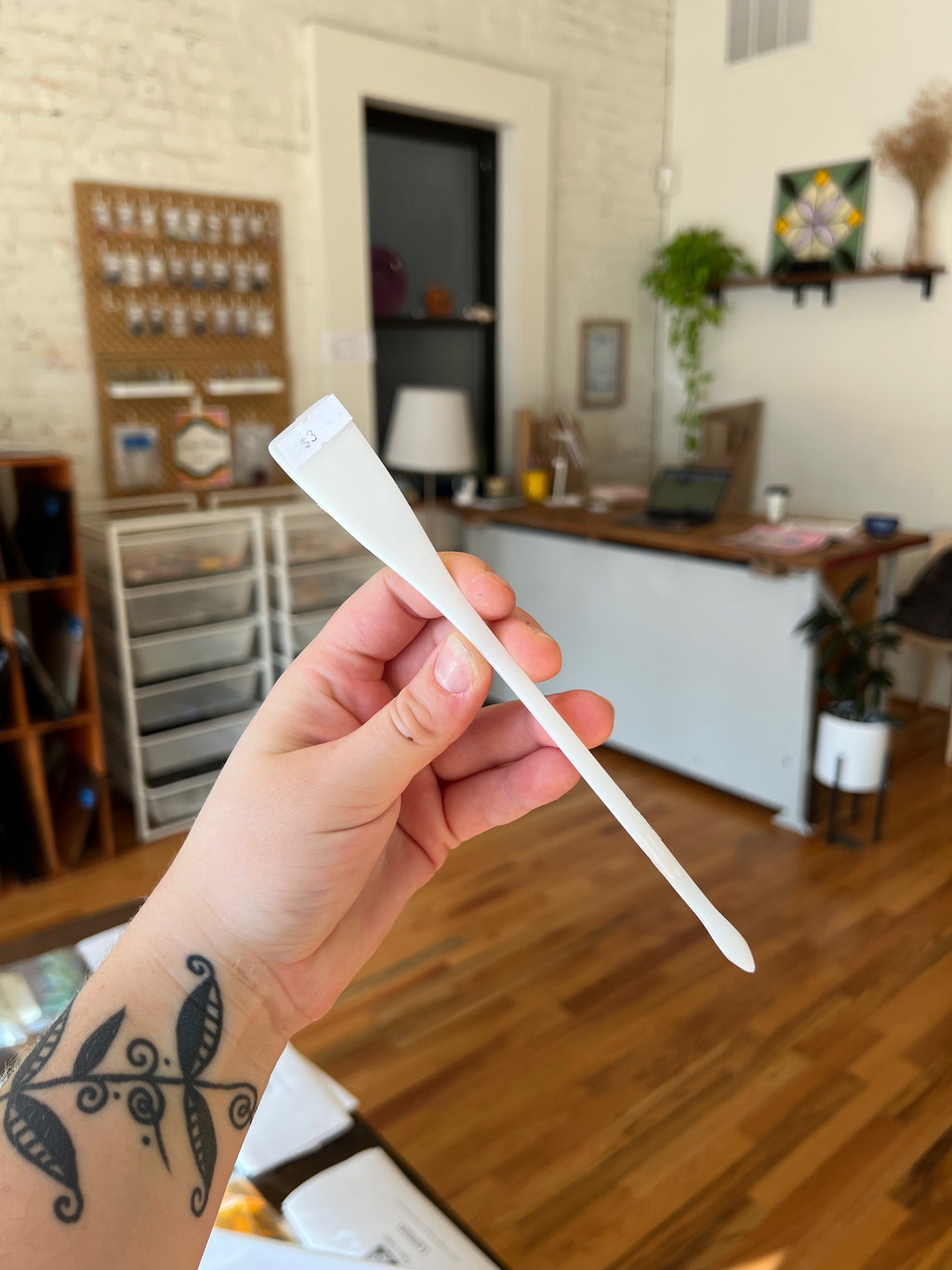 Hand holding a white plastic tool with a blurred indoor background