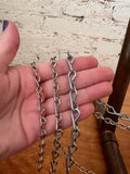 Hand holding two metal chains against a textured wall background