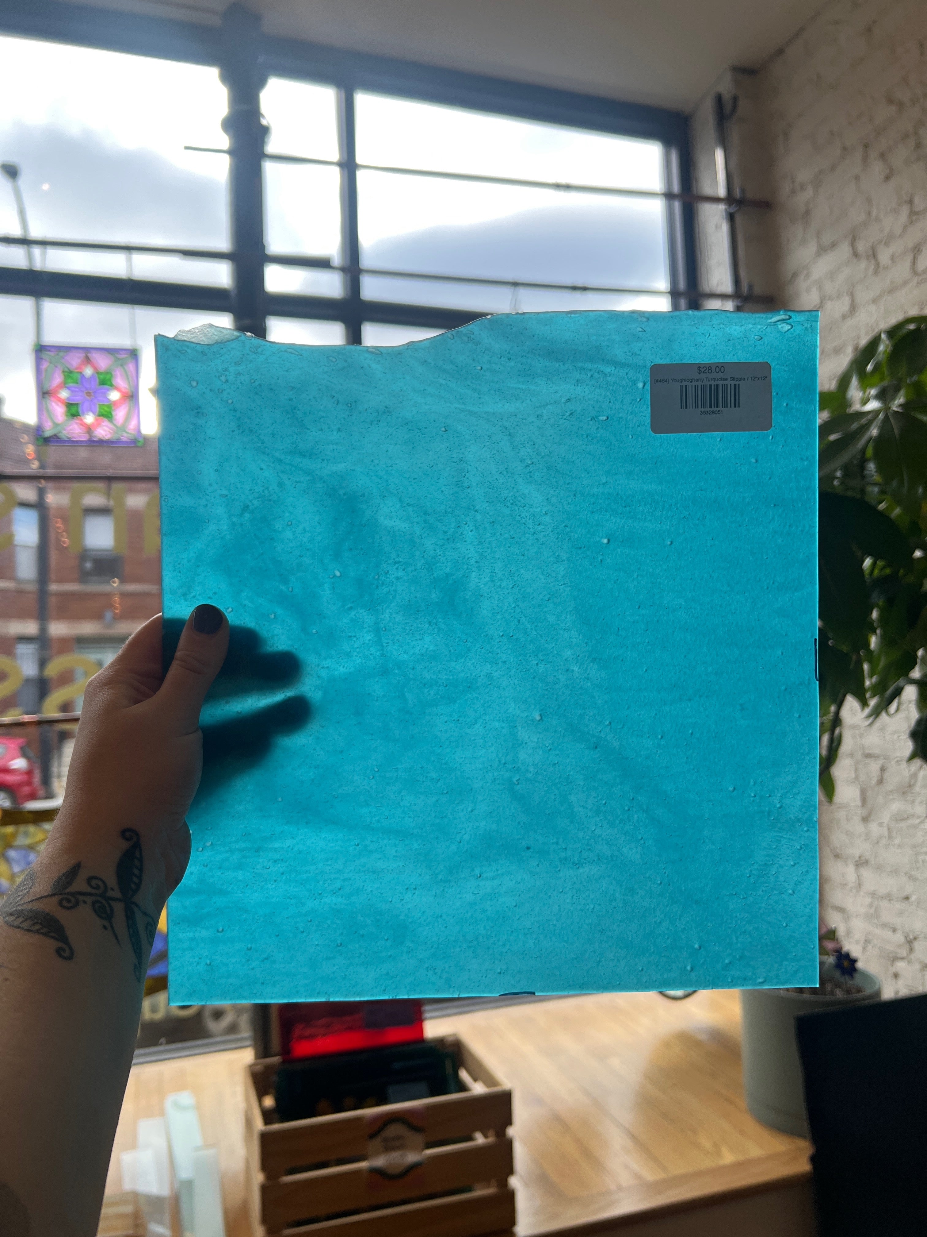 Hand holding a blue glass sheet with a windowed background