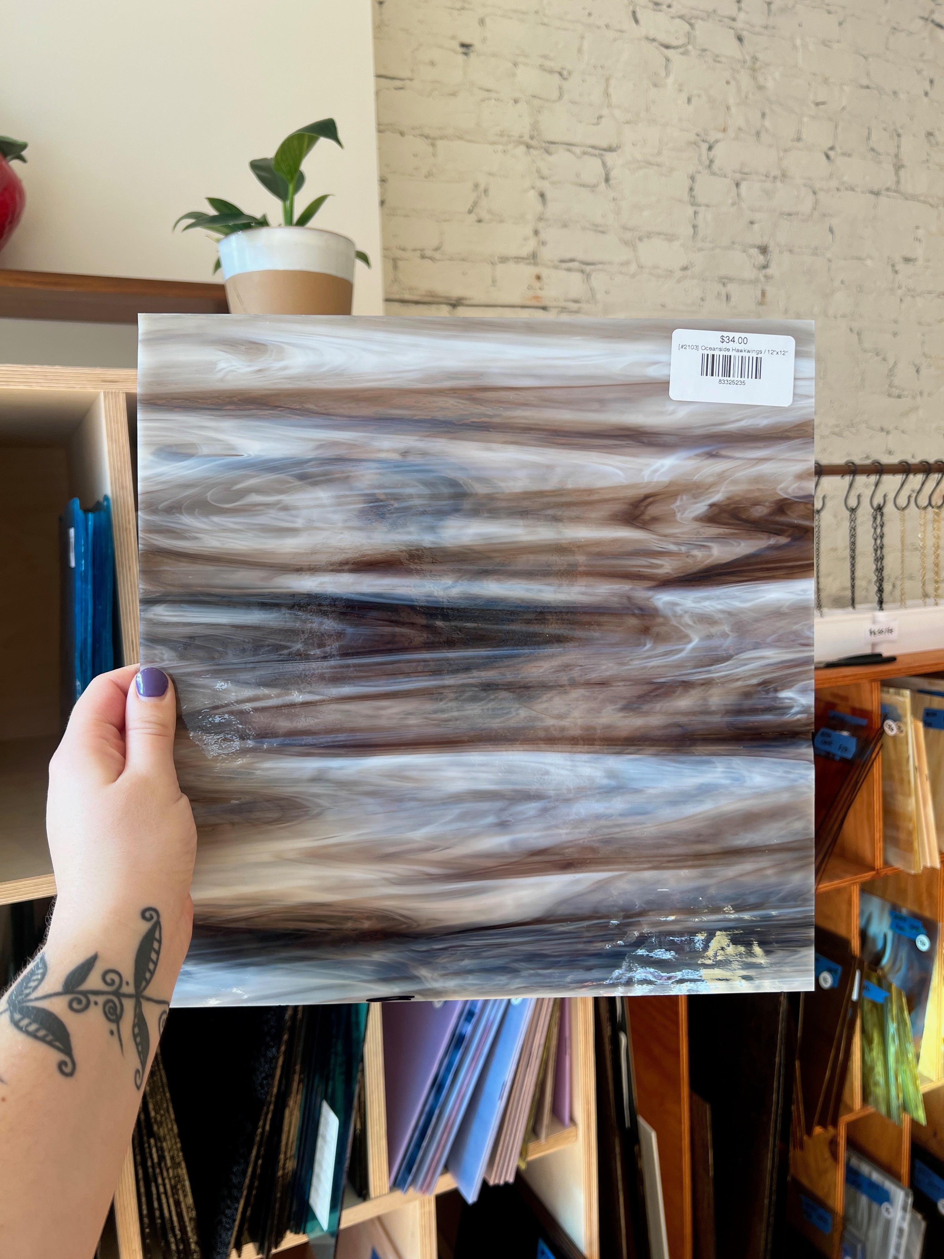 Person holding a wood-patterned sheet of glass with a blurred indoor background