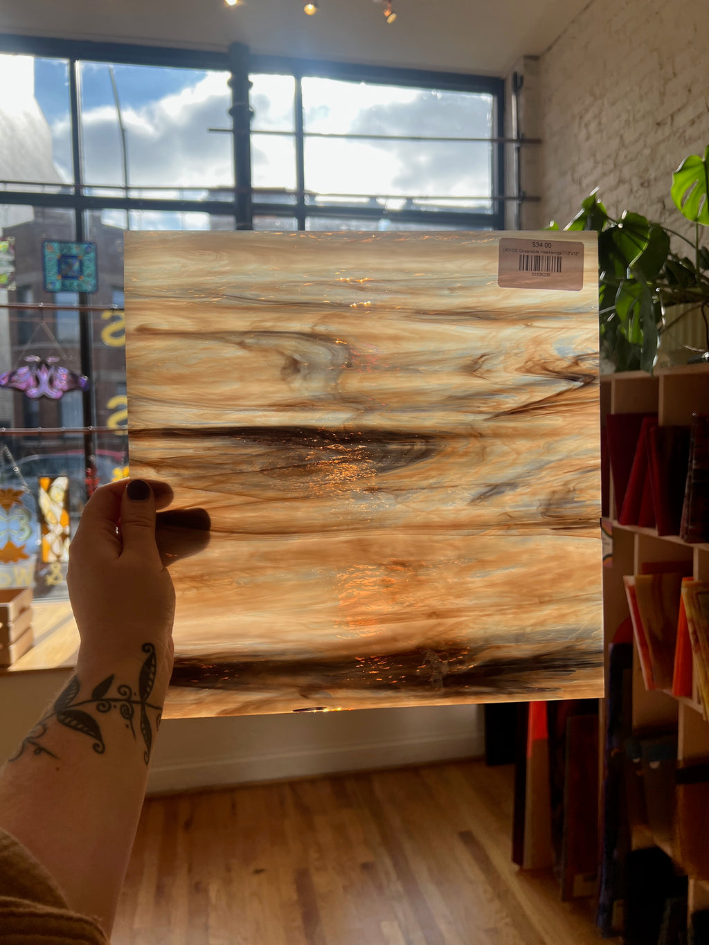 Person holding a wooden patterned sheet of glass with a blurred indoor background