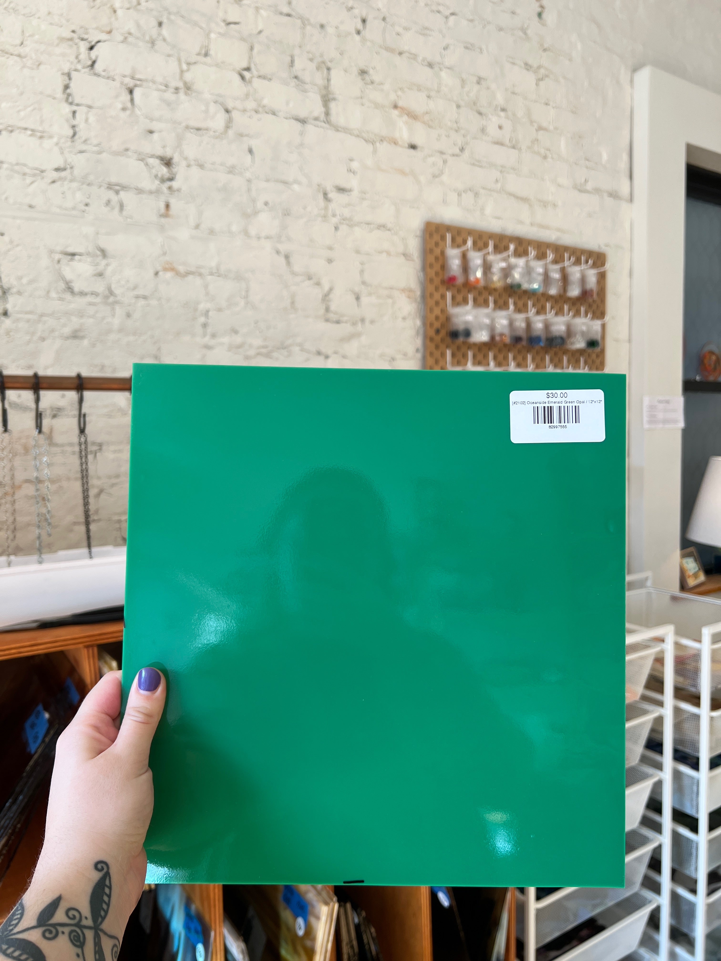 Person holding a green sheet of glass with a brick wall background
