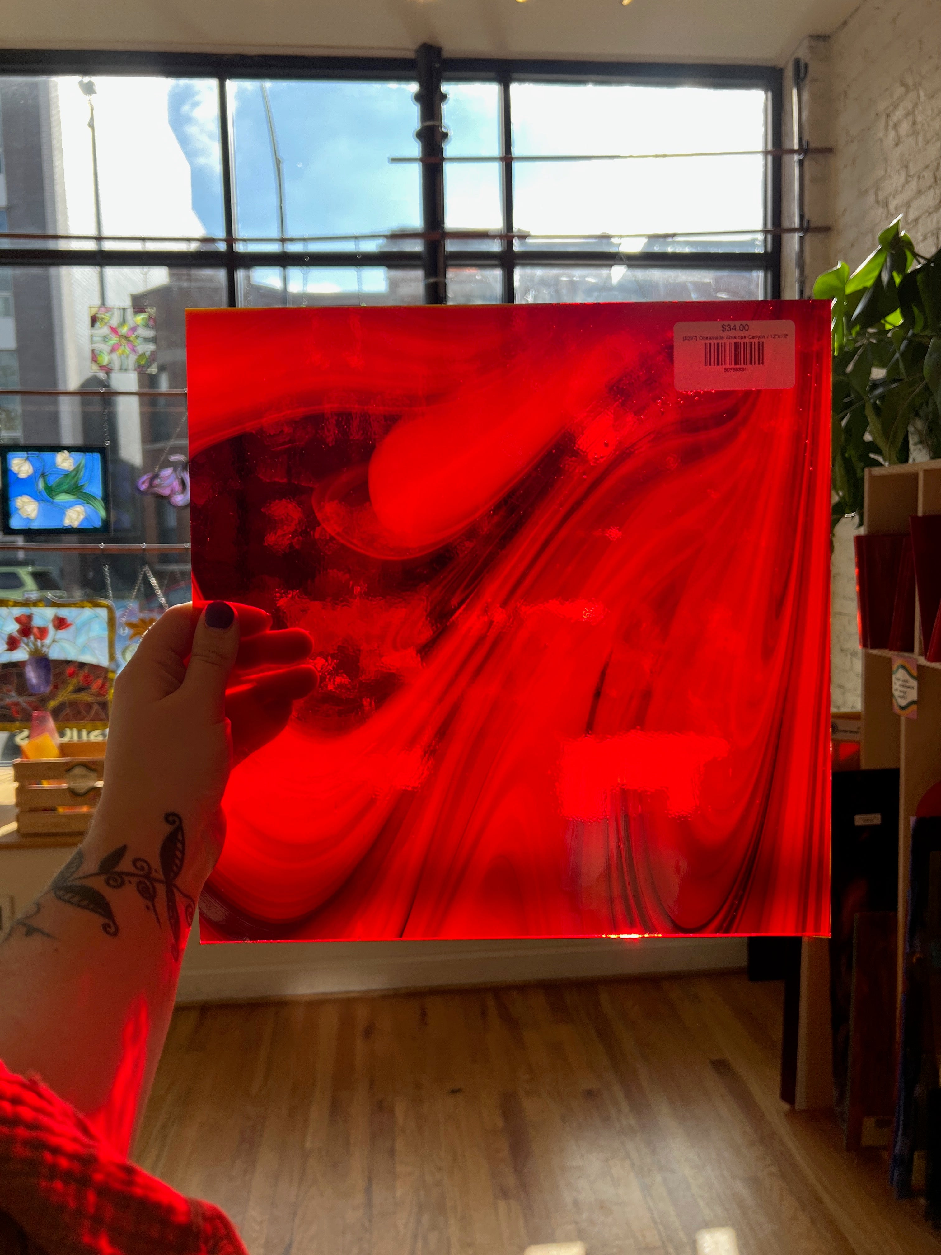 Person holding a red glass sheet with a pattern, indoor setting