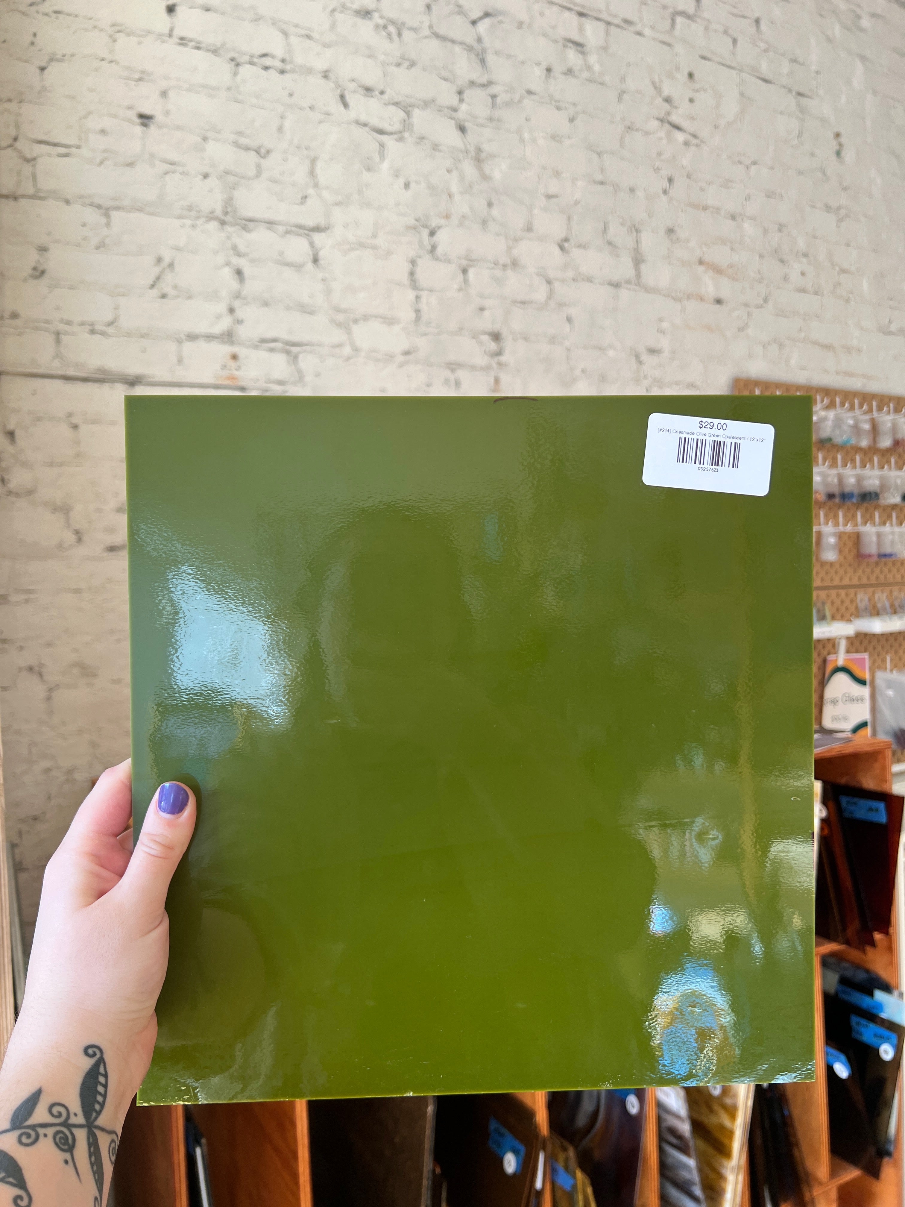 Green sheet of glass held by a person with a blurred background