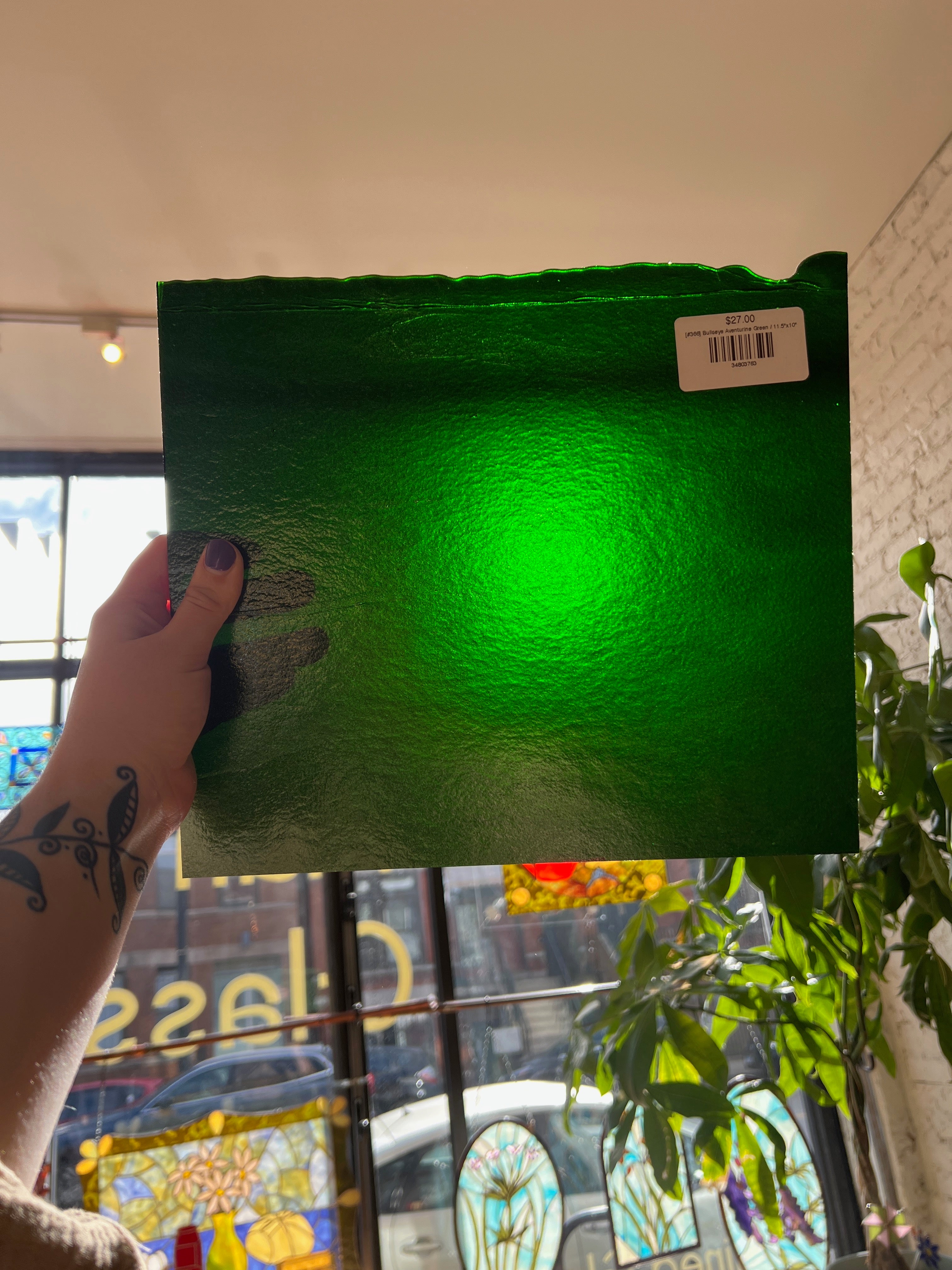 Green textured sheet glass held by a person with a blurred indoor background
