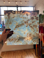 Rust-patterned glass held up in front of a room with plants.