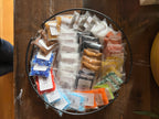 Assorted small glass frit packages on a round metal tray on a wooden surface