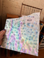 Iridescent sheet glass with a visible price tag held by a hand.