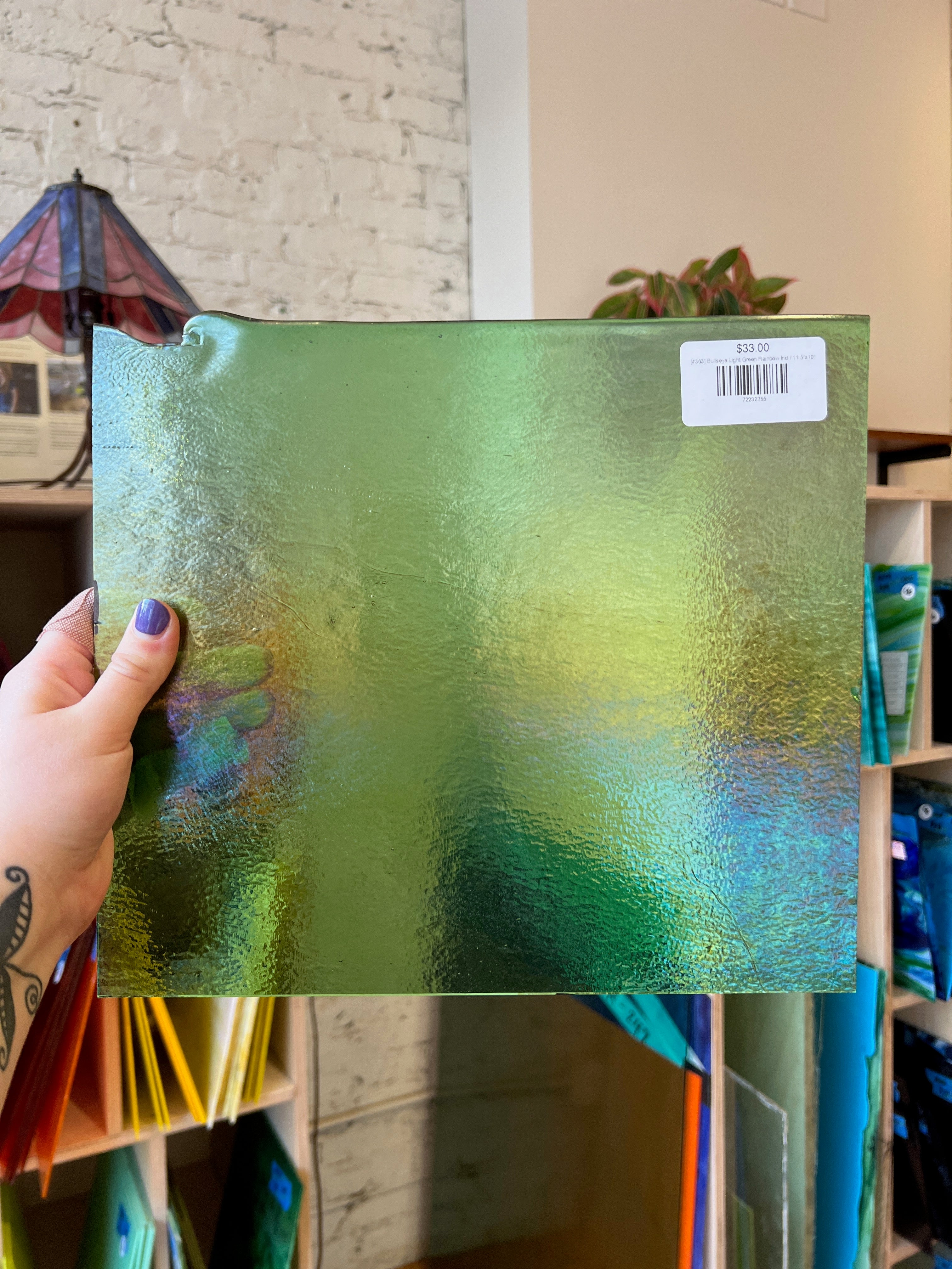 Green textured glass held by a hand with a blurred indoor background