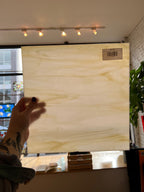 Person holding a glass panel with a visible brand label indoors.