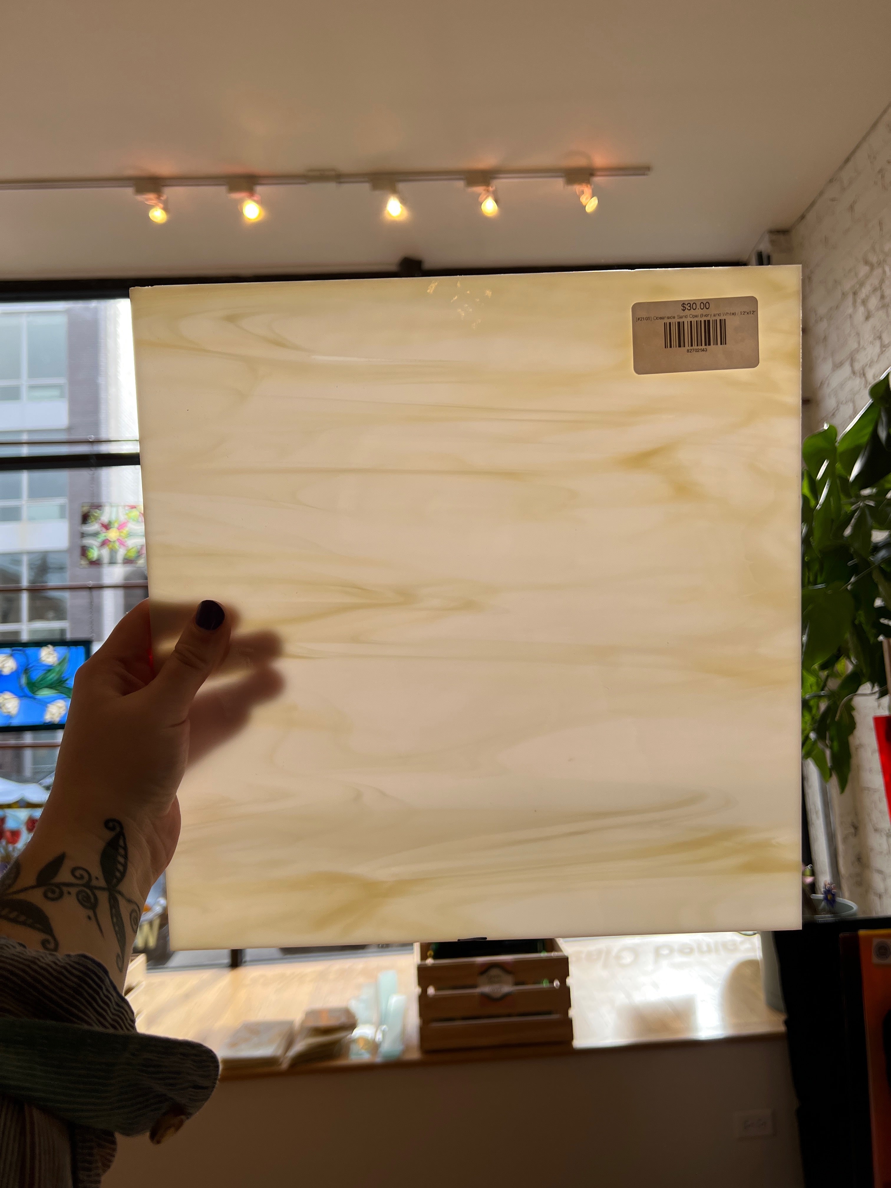 Person holding a glass panel with a visible brand label indoors.