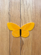 Yellow butterfly-shaped pieces of glass on a wooden surface