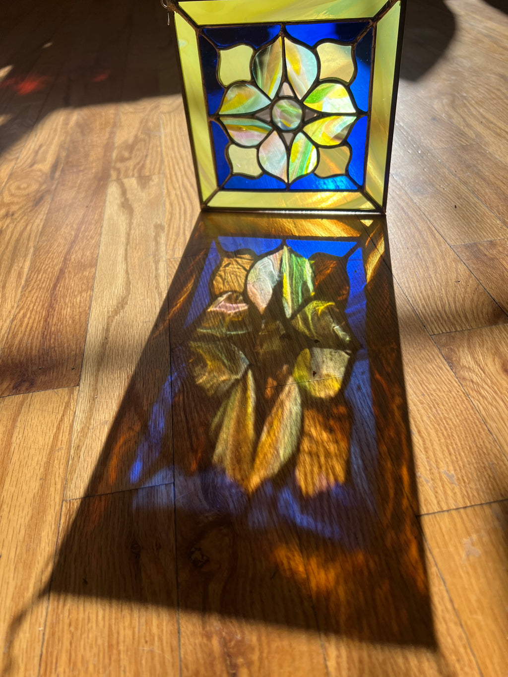 Stained glass panel with floral design on a wooden surface