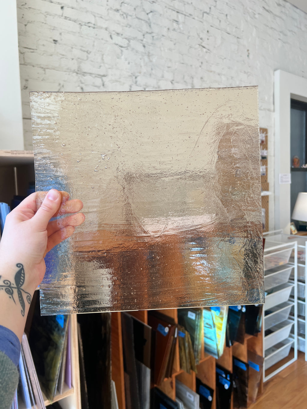 Hand holding a rectangular piece of textured glass indoors