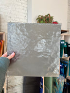 Person holding a textured gray piece of glass in a store setting