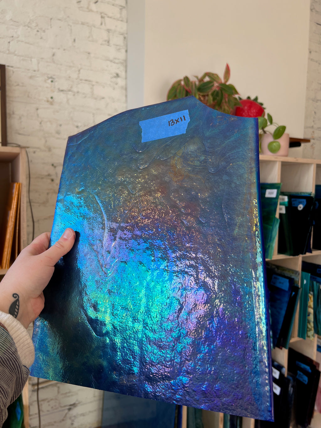 Person holding a blue iridescent piece of glass in a store setting