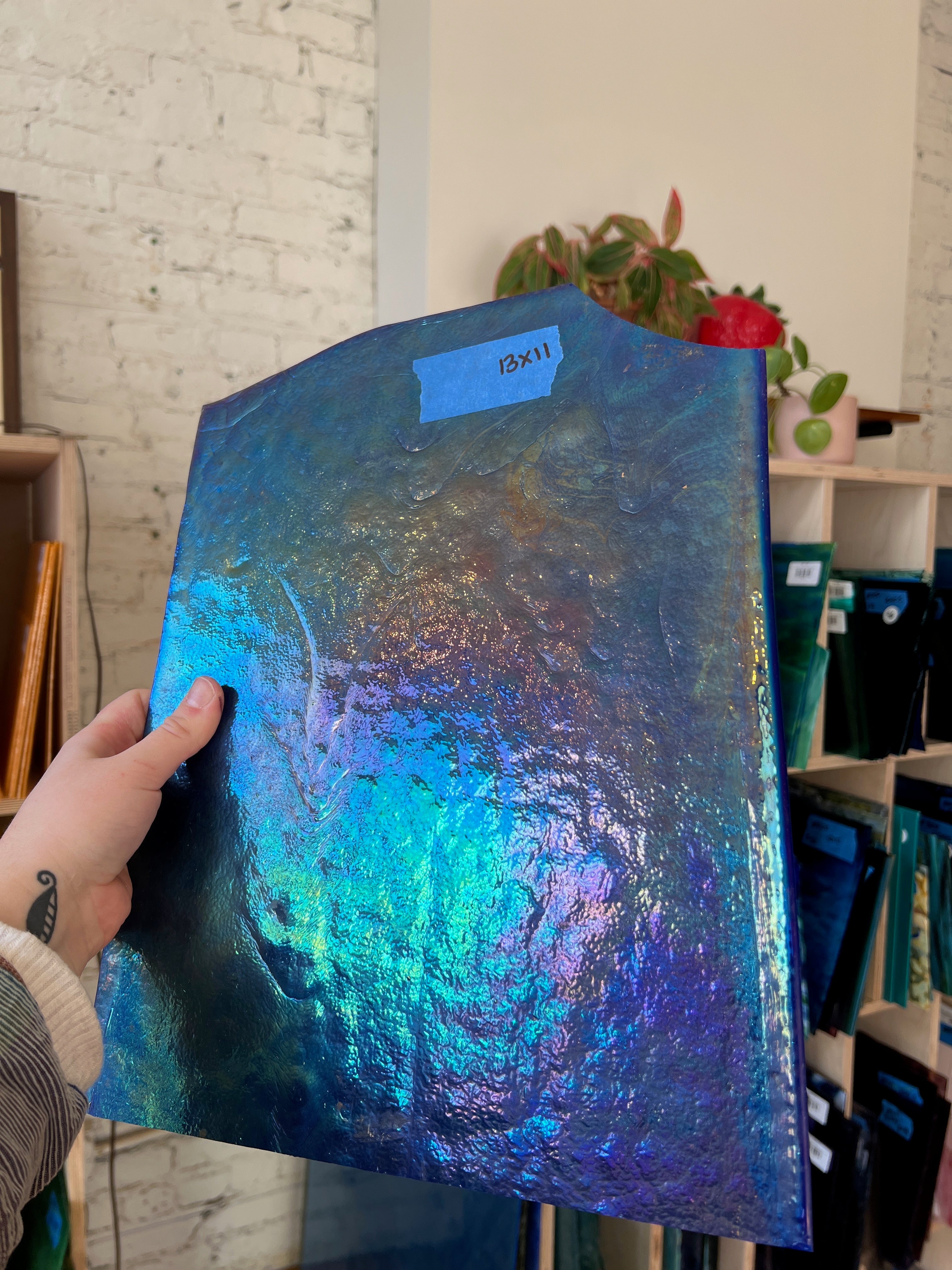 Person holding a blue iridescent piece of glass in a store setting