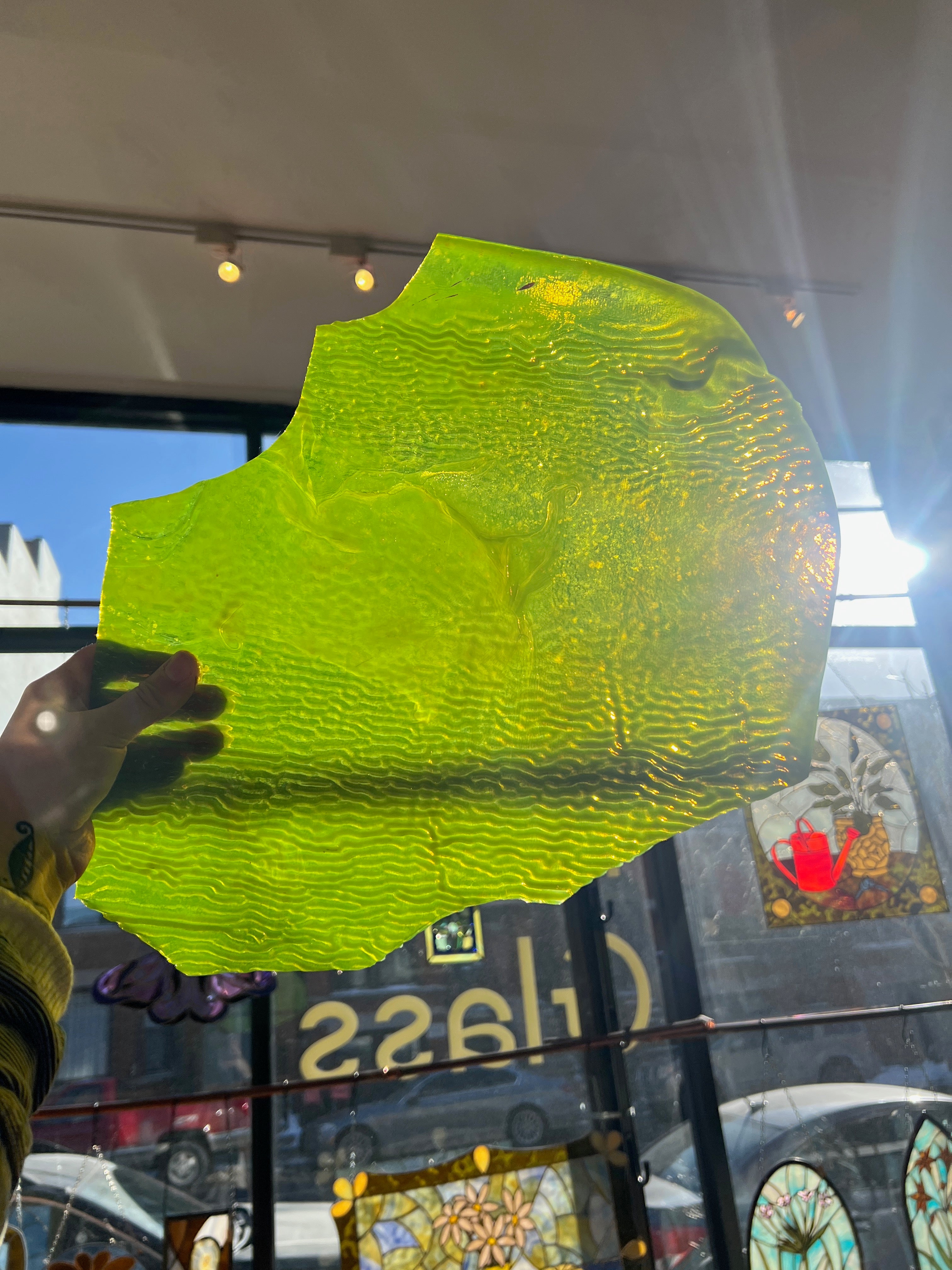 Large green piece of stained glass held up in front of a store window