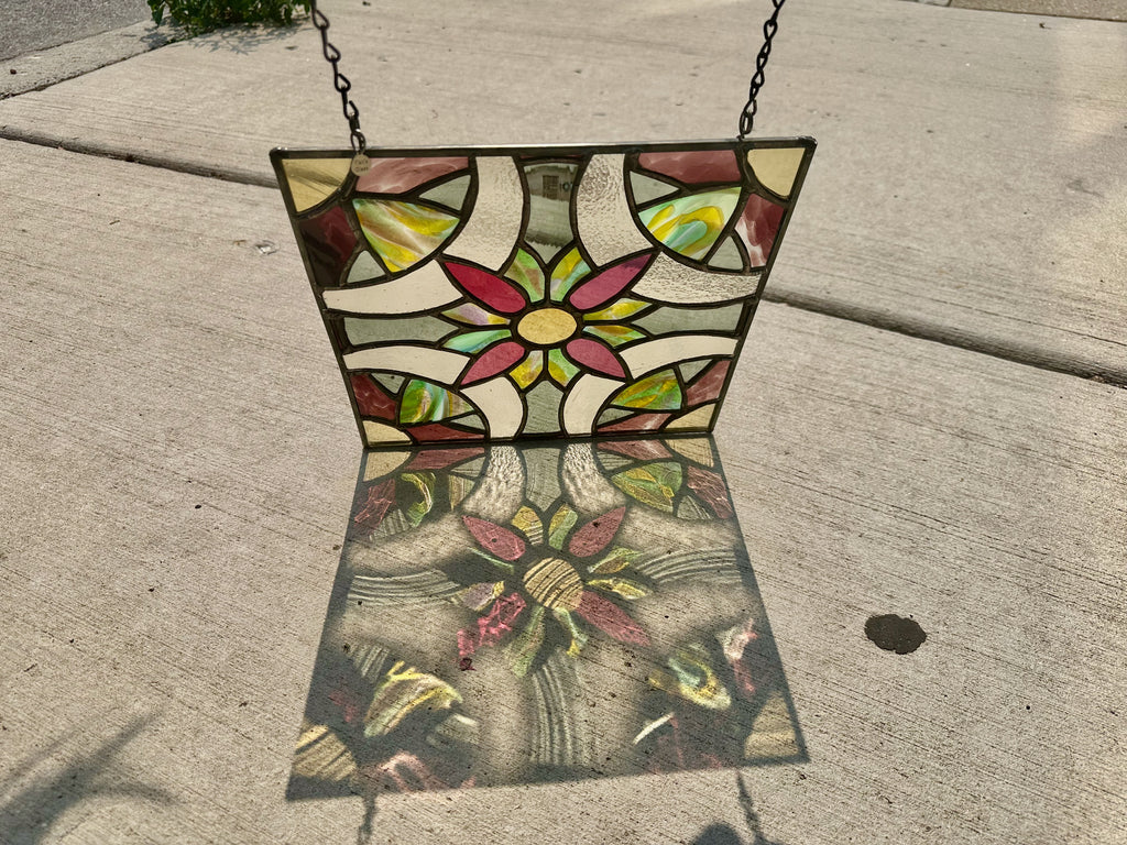 Stained glass panel with floral design on a concrete surface