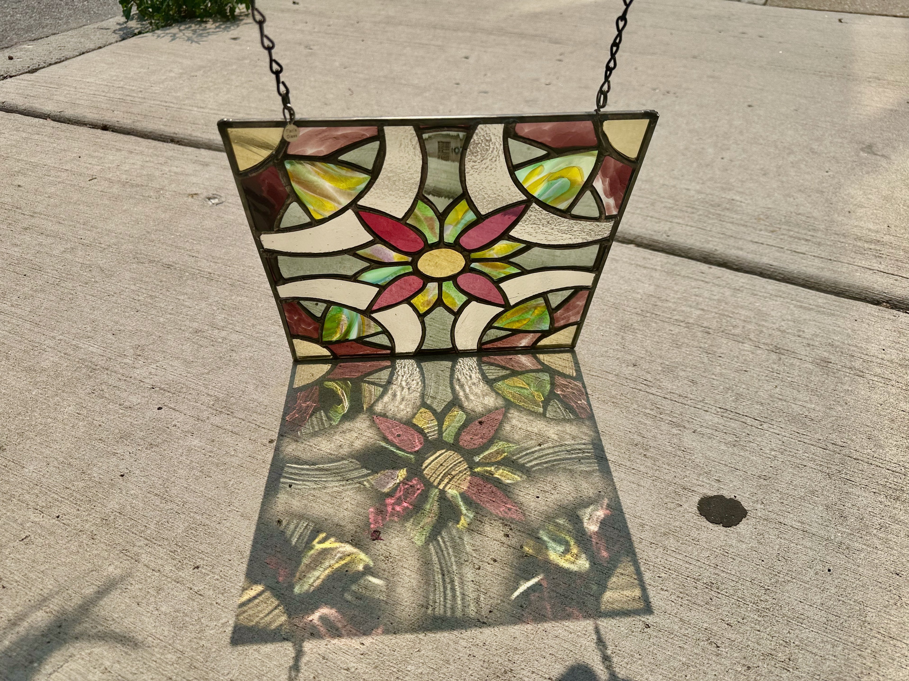 Stained glass panel with floral design on a concrete surface