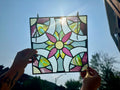Colorful stained glass panel held up against a blue sky